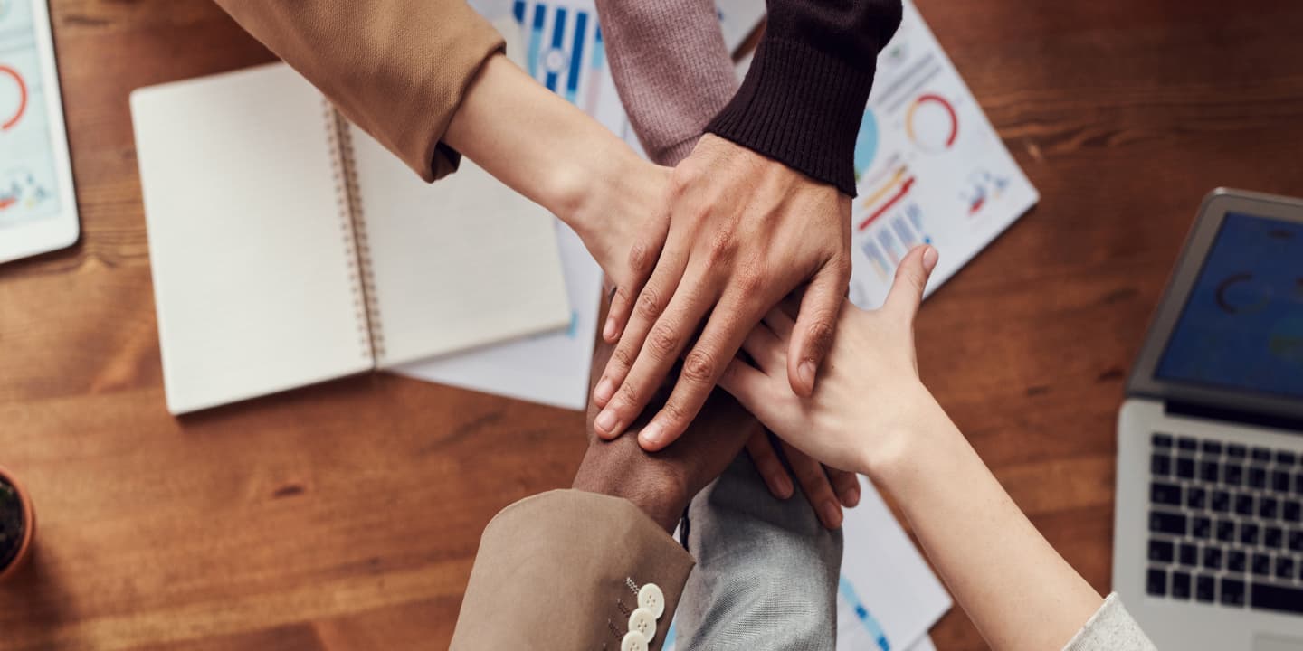 team unites hands over desk